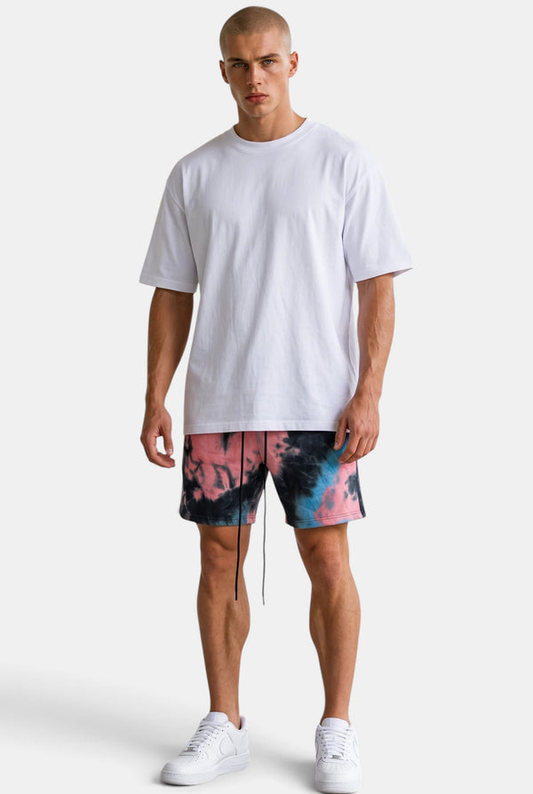 KIOKO Cypher tie-dye jogger shorts in blue and pink cotton with an elastic drawstring waist worn by a male model.